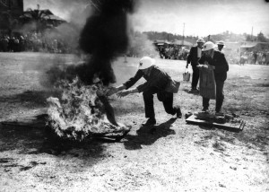 Wardens attacking an oil incendiary bomb with sand-mats during the Rosalie-Torwood inter-zone A.R.P.competition (description supplied with photograph). (John Oxley Library, State Library of Queensland Neg: 109837)